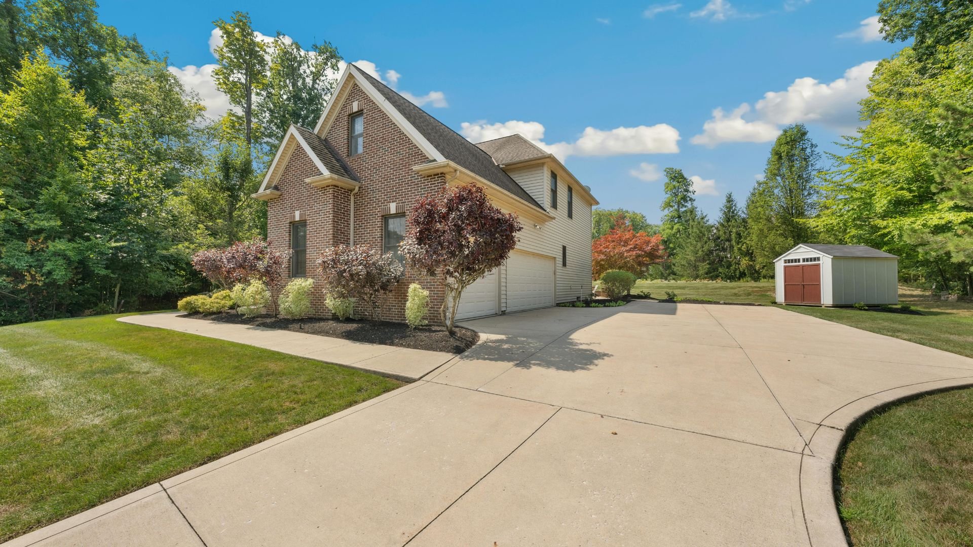Brick and siding two-story house with curved driveway and landscaped yard