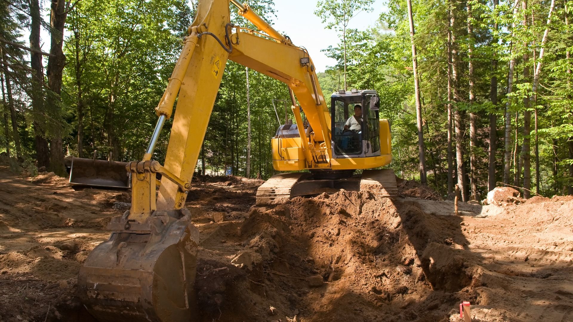 Yellow excavator digging earth in forest construction site