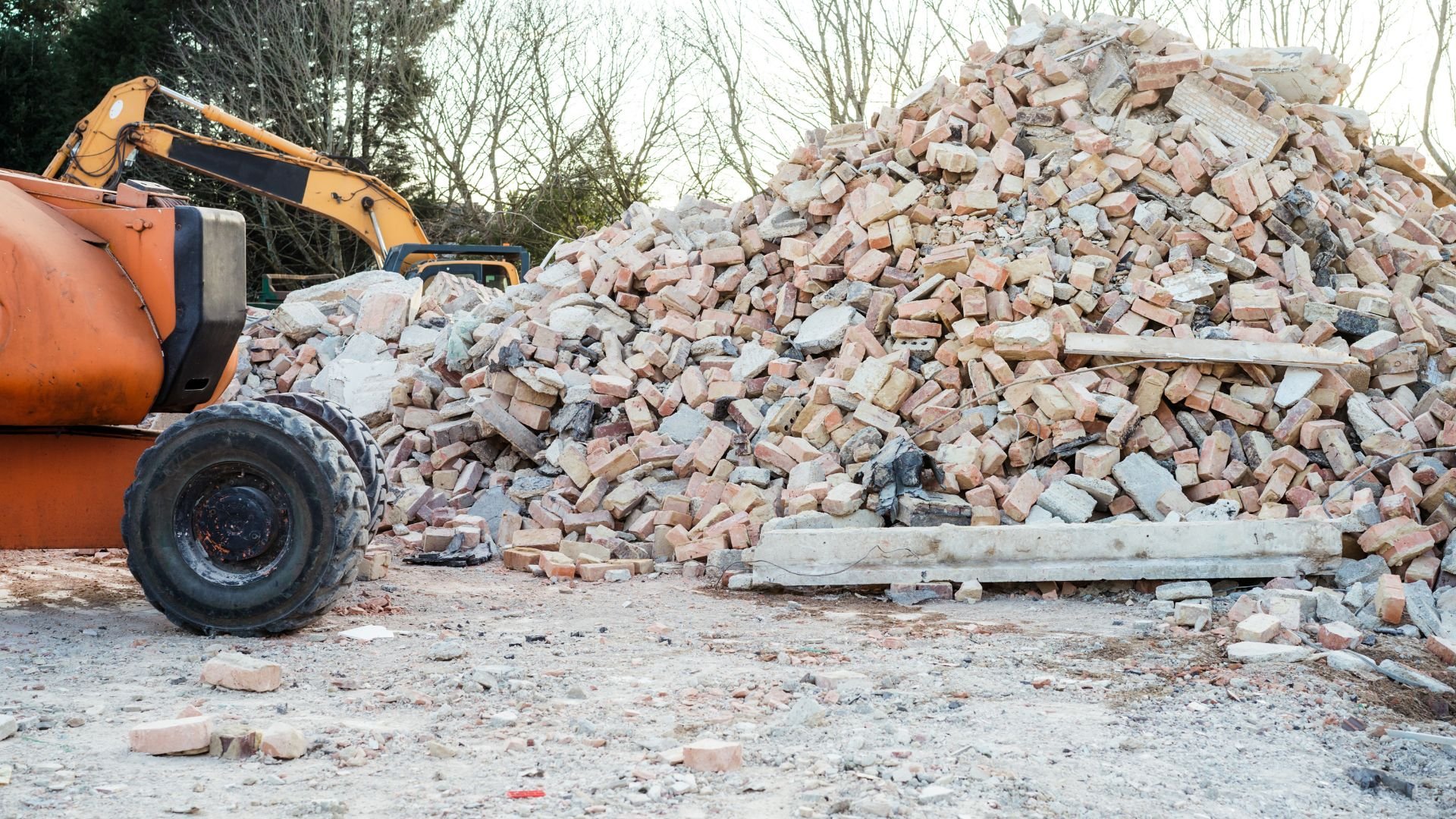 Large pile of broken bricks and concrete with construction equipment nearby